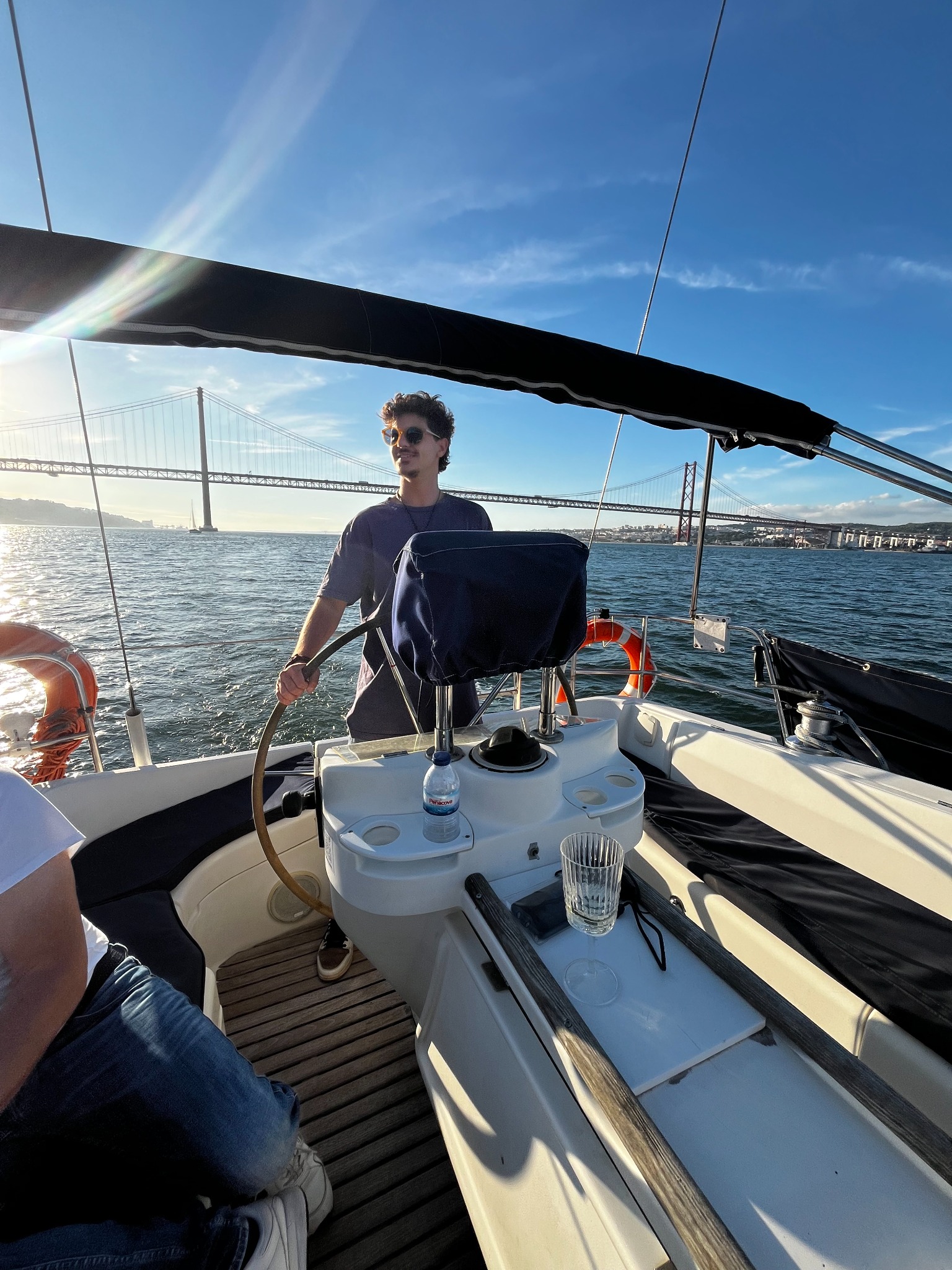 At the helm with the 25 de Abril Bridge behind